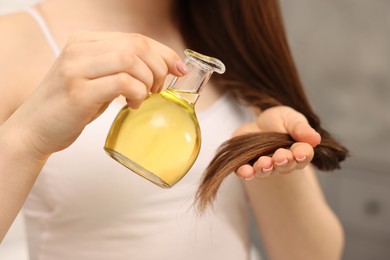 Photo of Woman applying oil hair mask indoors, closeup