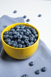 Photo of Crockery with juicy and fresh blueberries on white table