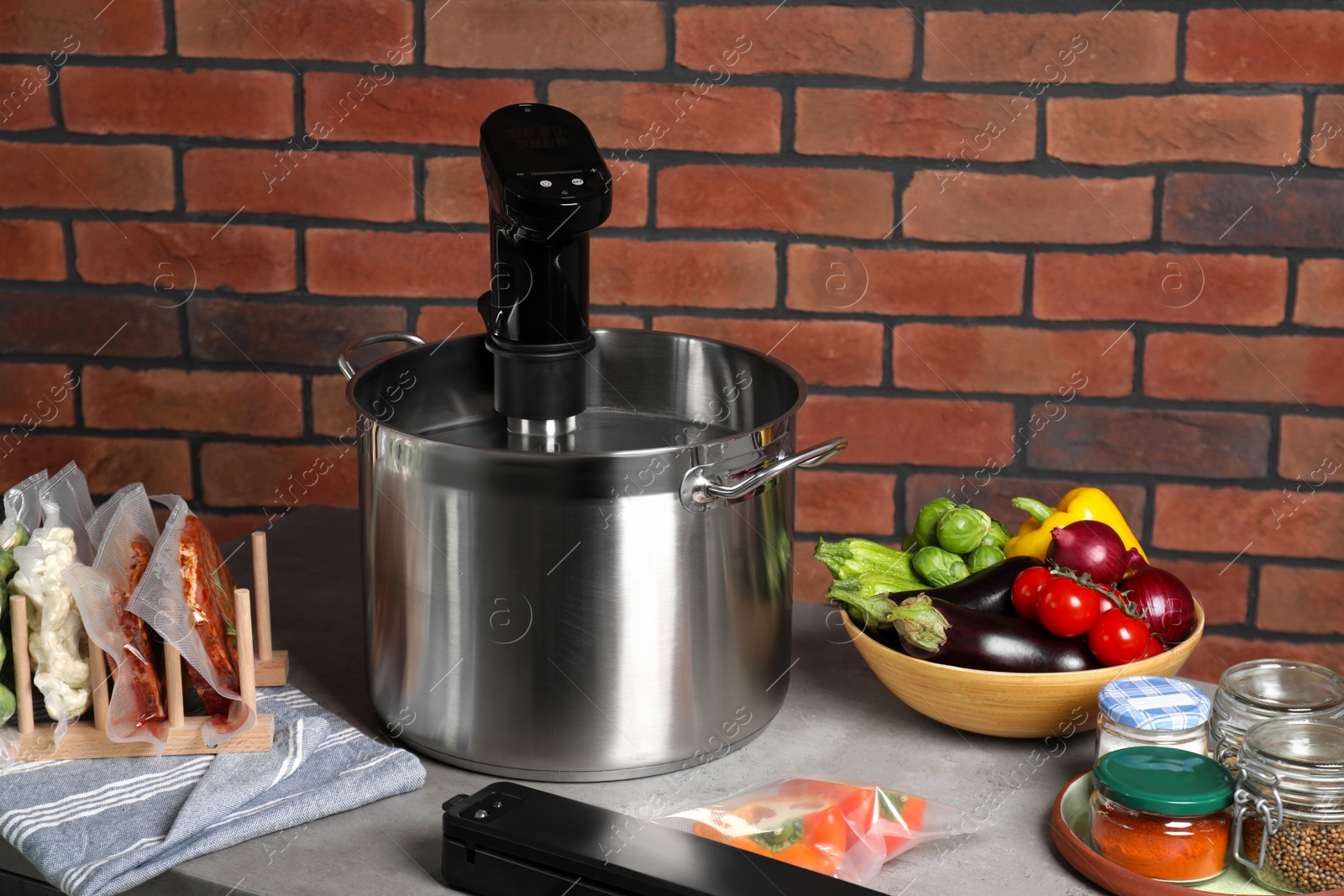 Photo of Thermal immersion circulator in pot and ingredients on beige table. Vacuum packing for sous vide cooking