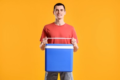 Man with blue cool box on orange background