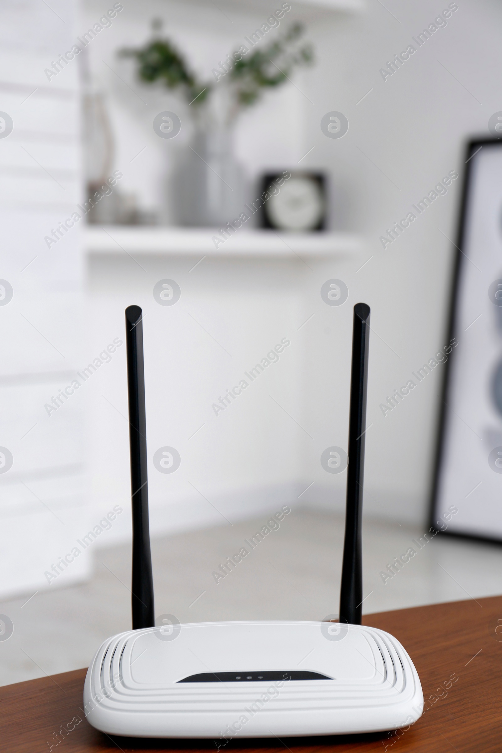 Photo of Modern Wi-Fi router on wooden table indoors