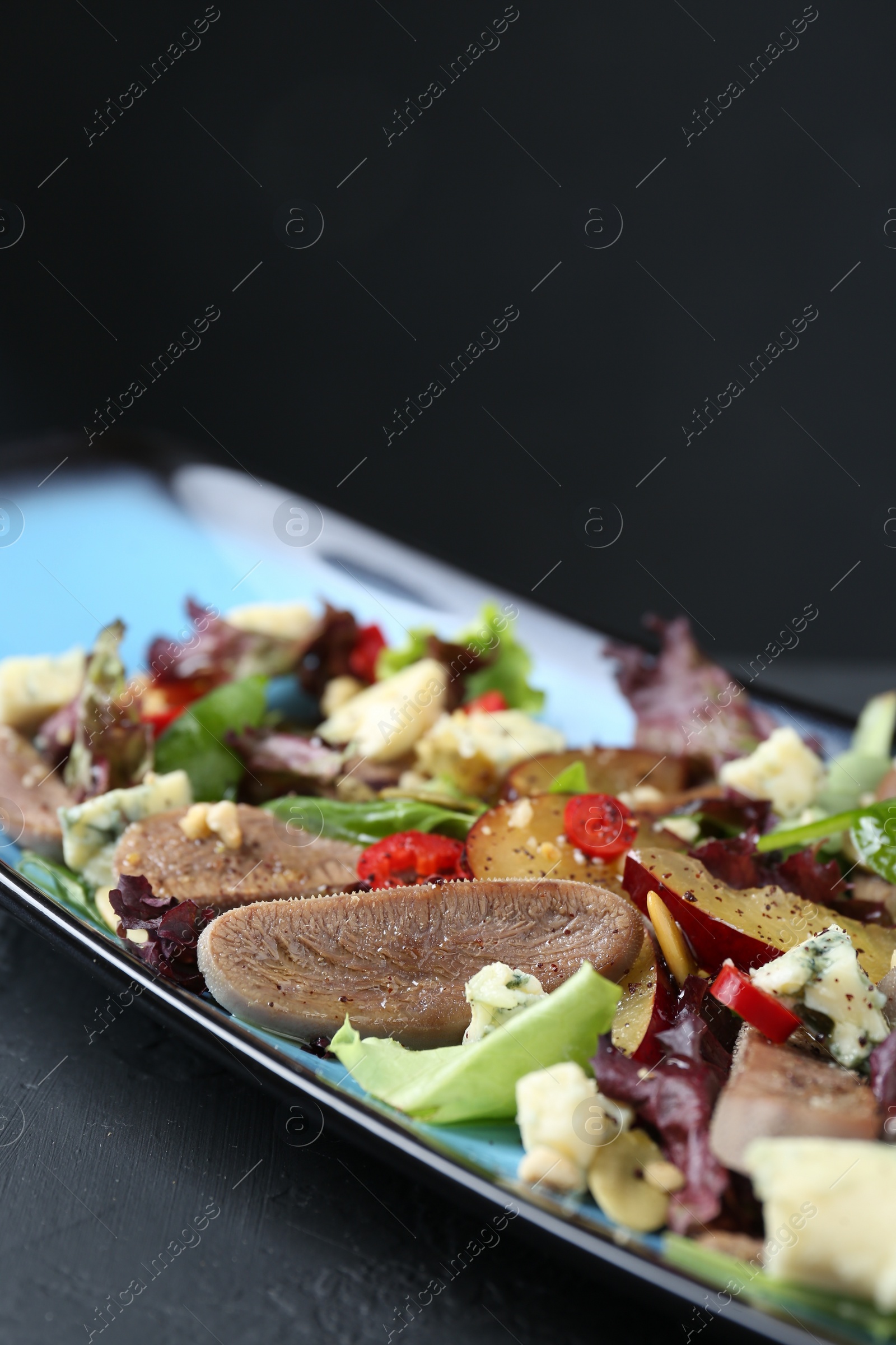 Photo of Delicious salad with beef tongue and cheese on black table, closeup
