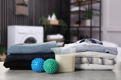 Image of Dryer balls, detergent and stacked clean clothes on table in laundry room