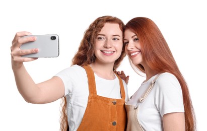 Photo of Beautiful young redhead sisters taking selfie on white background