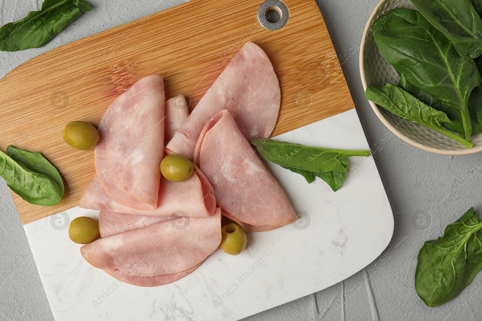 Photo of Ham with olives and spinach on light grey table, flat lay