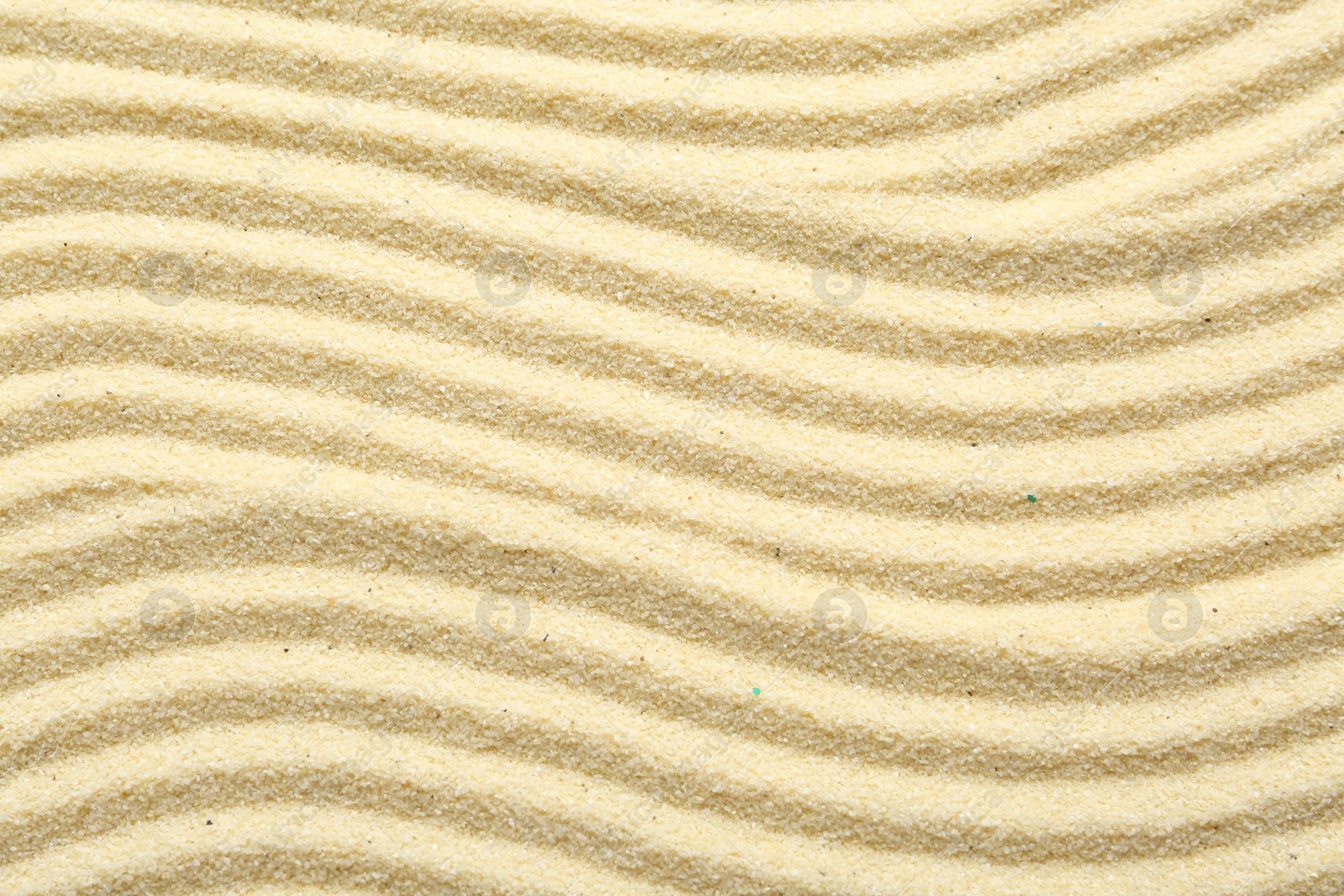 Photo of Zen rock garden. Wave pattern on beige sand, top view