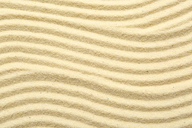 Photo of Zen rock garden. Wave pattern on beige sand, top view