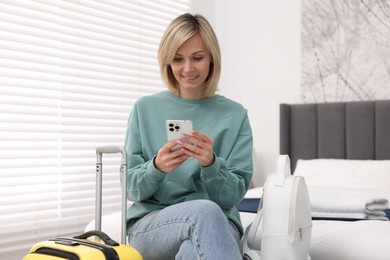 Photo of Smiling guest with smartphone in stylish hotel room