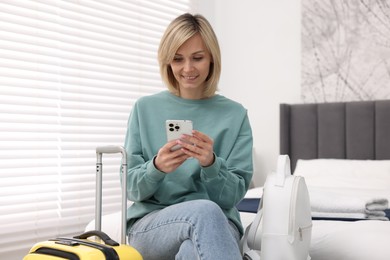 Smiling guest with smartphone in stylish hotel room