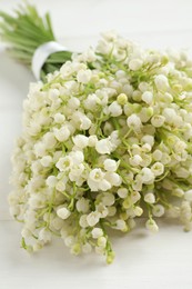 Photo of Beautiful lily of the valley bouquet on white wooden table, closeup