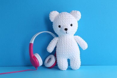 Baby songs. Toy bear and headphones on light blue background