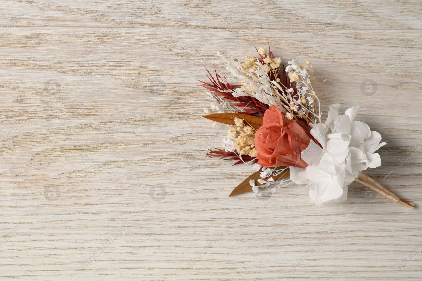 Photo of Stylish boutonniere on white wooden table, top view. Space for text