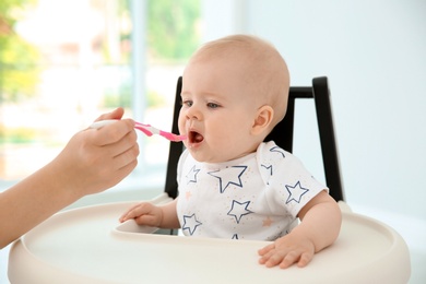 Mother feeding her cute little baby at home