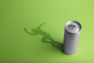 Image of Energy drink and shadow in shape of sportsman's silhouette on light green background 
