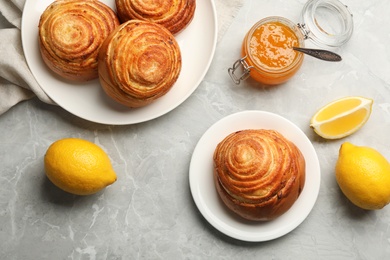 Flat lay composition with buns, lemons and jam on grey stone background. Fresh from oven