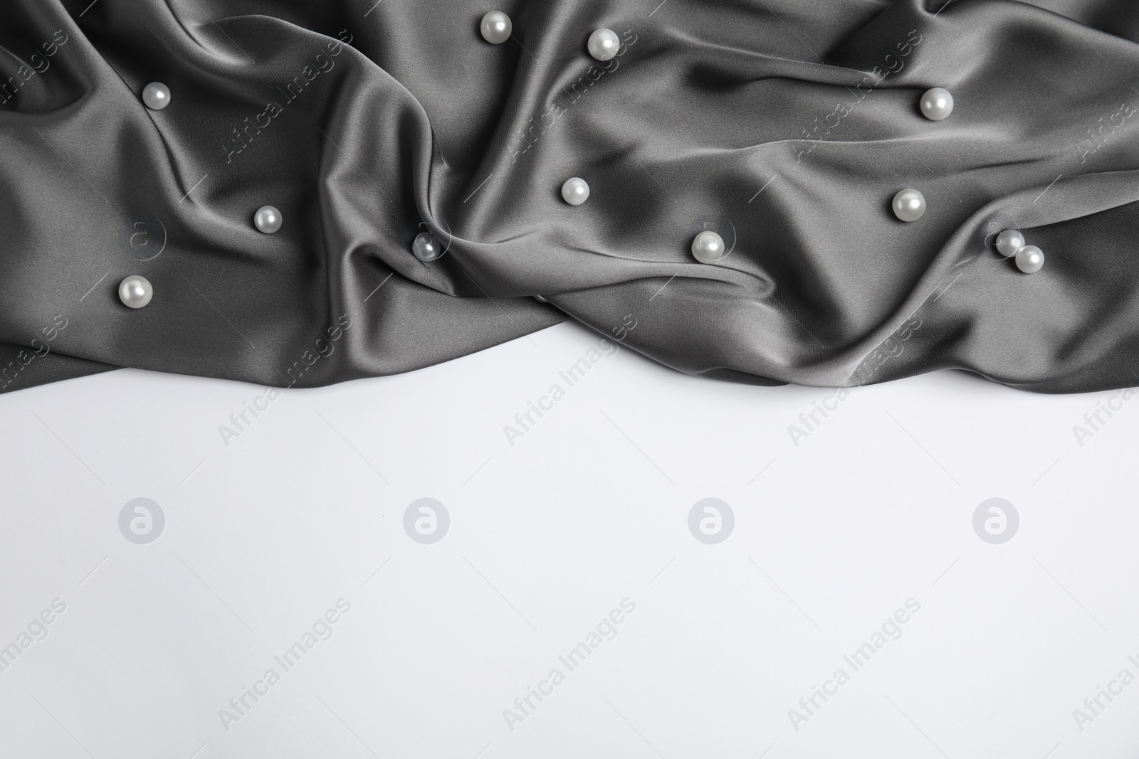 Photo of Texture of delicate black silk with pearls on white background