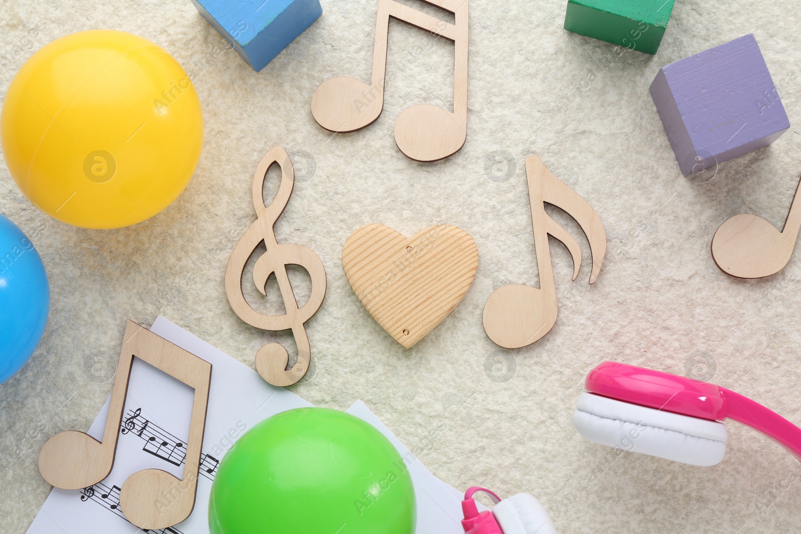 Photo of Wooden notes, music sheets and toys on beige textured background, flat lay. Baby song concept