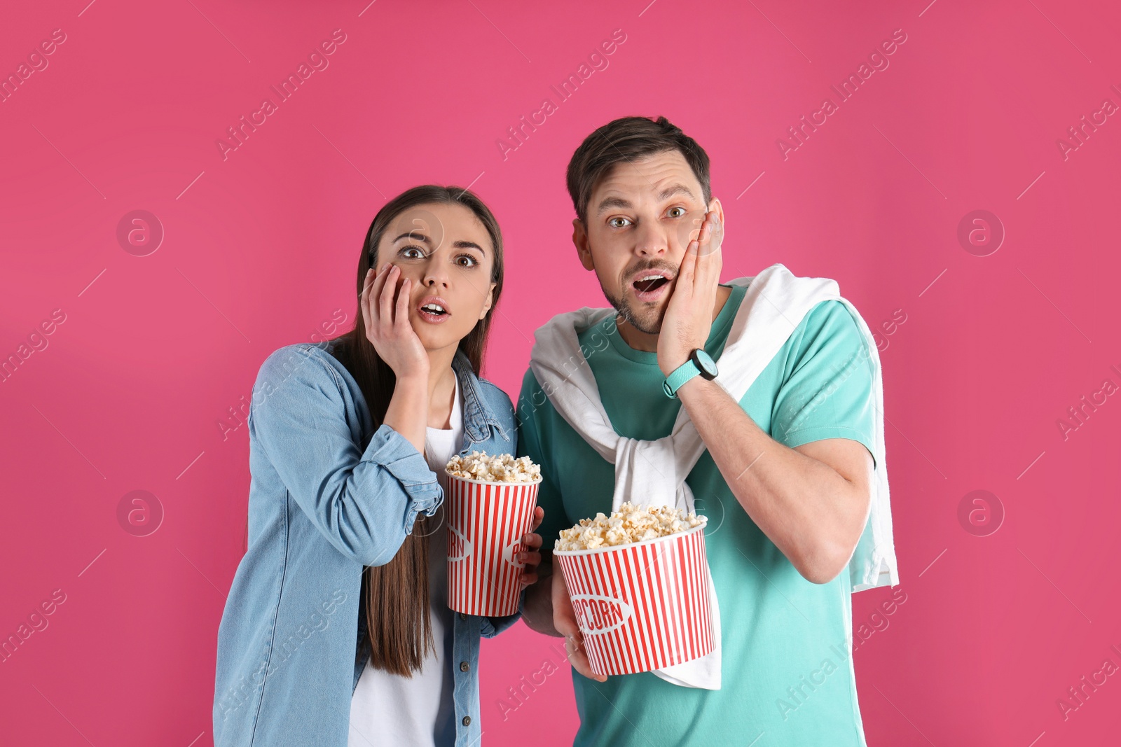 Photo of Emotional couple with tasty popcorn on color background