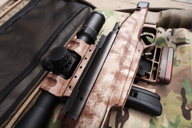 Photo of Modern powerful sniper rifle with telescopic sight on camouflage fabric, closeup