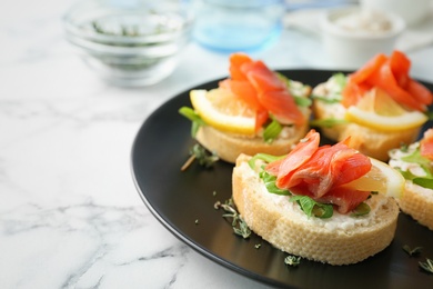 Photo of Tasty sandwiches with fresh sliced salmon fillet on plate, closeup