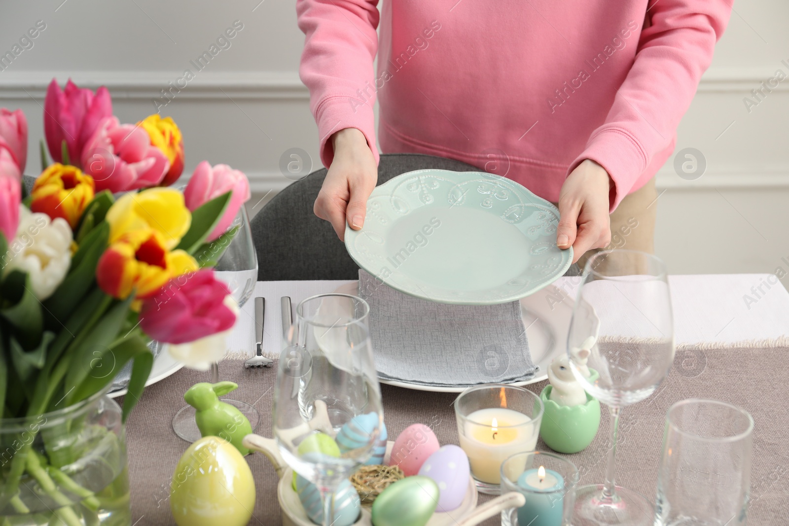 Photo of Woman setting table for festive Easter dinner at home, closeup