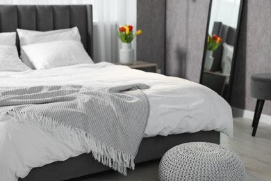 Stylish bedroom interior with large bed and pouf
