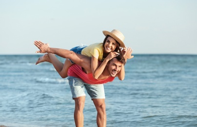 Happy young couple having fun at beach on sunny day