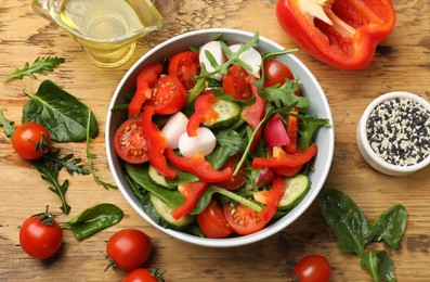 Photo of Tasty fresh vegetarian salad on wooden table, flat lay