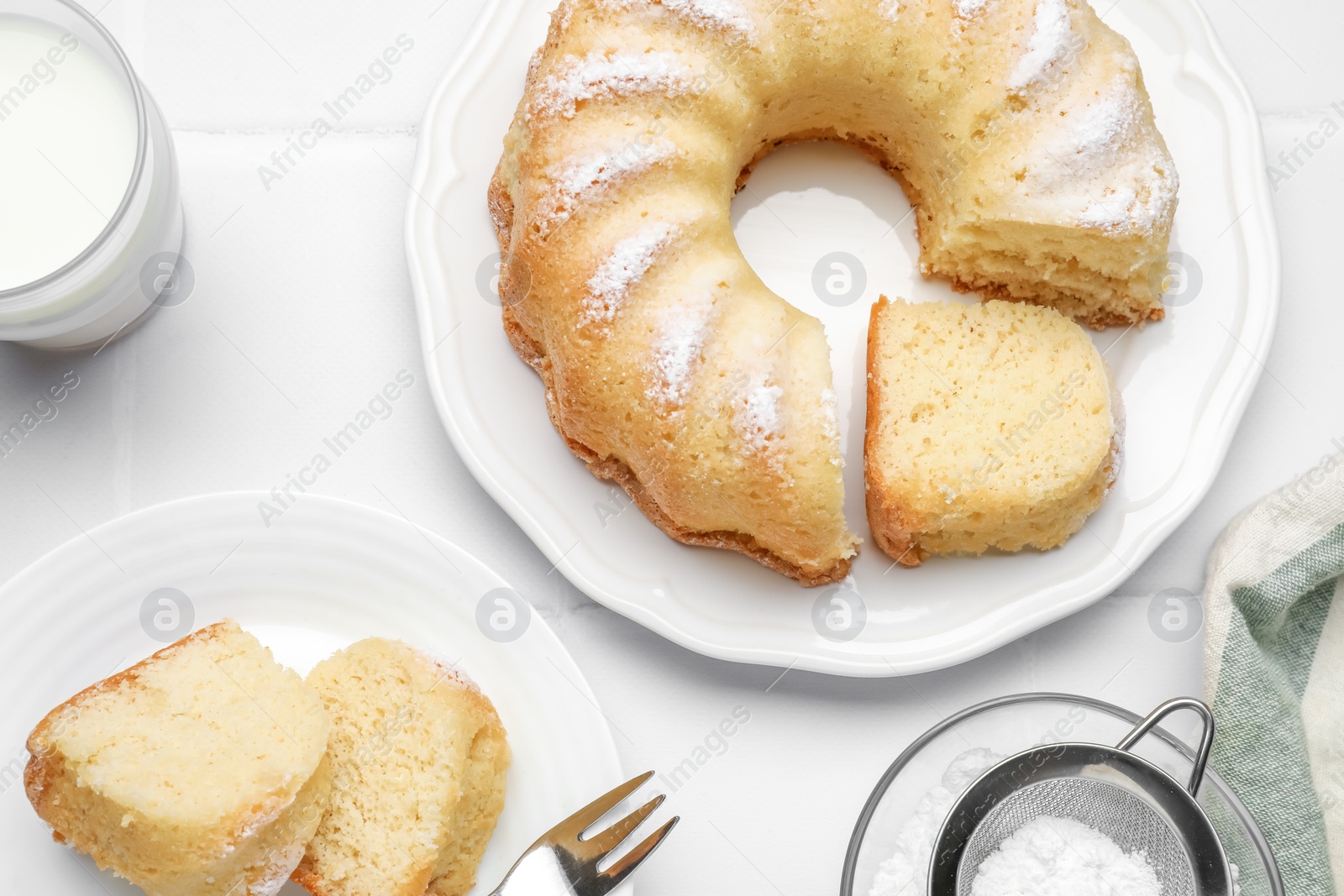 Photo of Delicious sponge cake served on white tiled table, flat lay