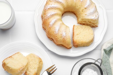 Photo of Delicious sponge cake served on white tiled table, flat lay