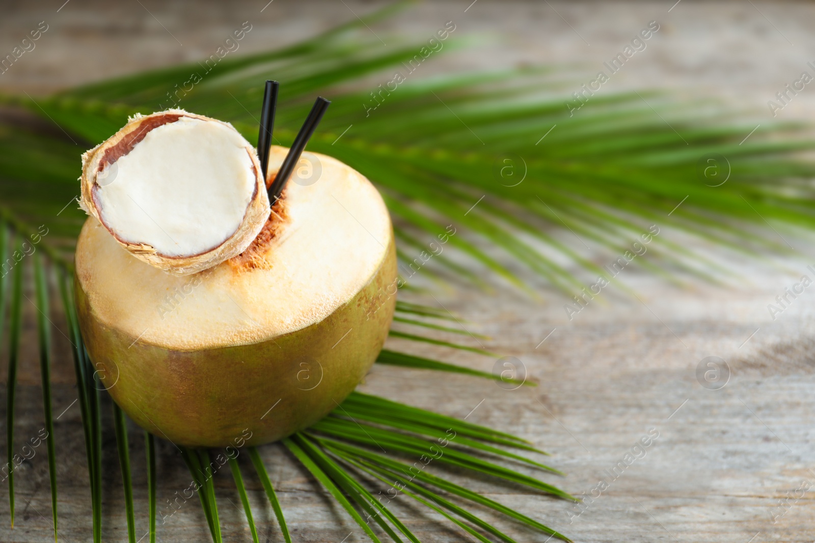 Photo of Fresh green coconut with drinking straws on wooden table