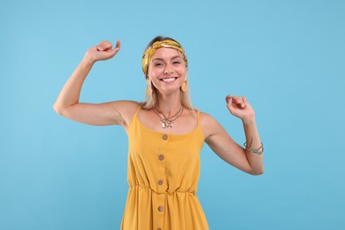 Photo of Portrait of smiling hippie woman dancing on light blue background