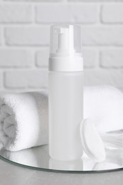 Photo of Bottle of face cleansing product, towel and cotton pads on grey table. Space for text