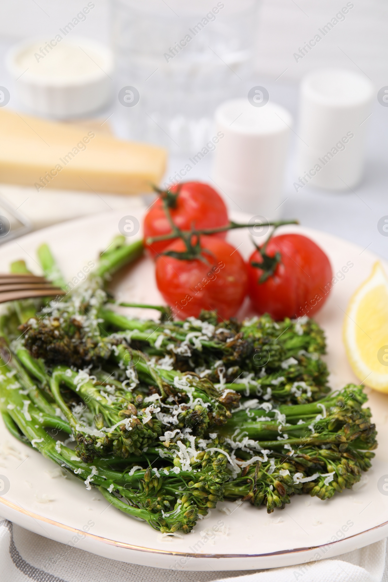 Photo of Tasty cooked broccolini with cheese and tomatoes on plate, closeup