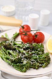 Tasty cooked broccolini with cheese and tomatoes on plate, closeup