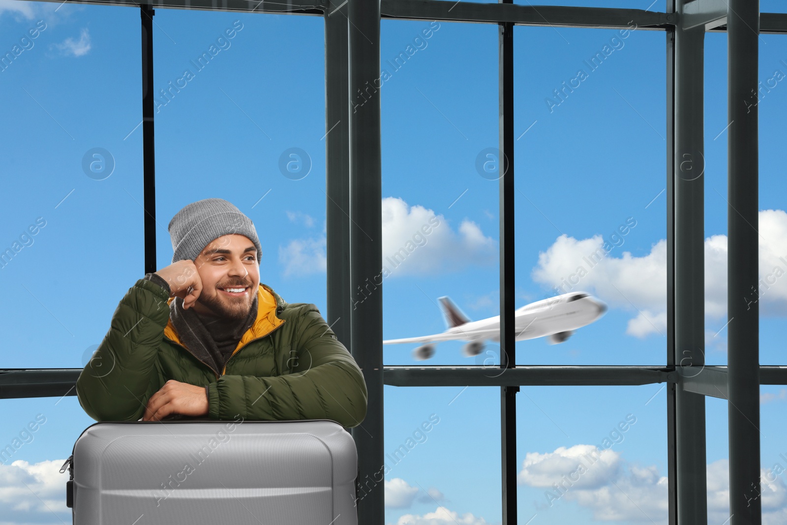 Image of Happy young man with suitcase in airport