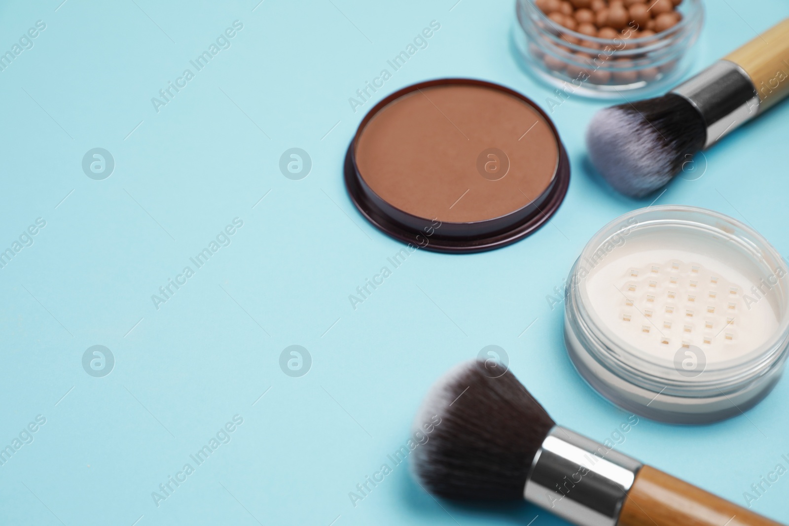 Photo of Different face powders and brushes on light blue background. Space for text