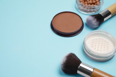 Photo of Different face powders and brushes on light blue background. Space for text