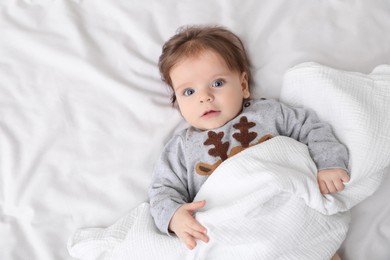 Photo of Cute little baby on soft bed, top view. Space for text