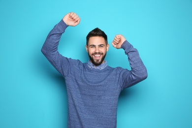 Photo of Happy young man celebrating victory on color background