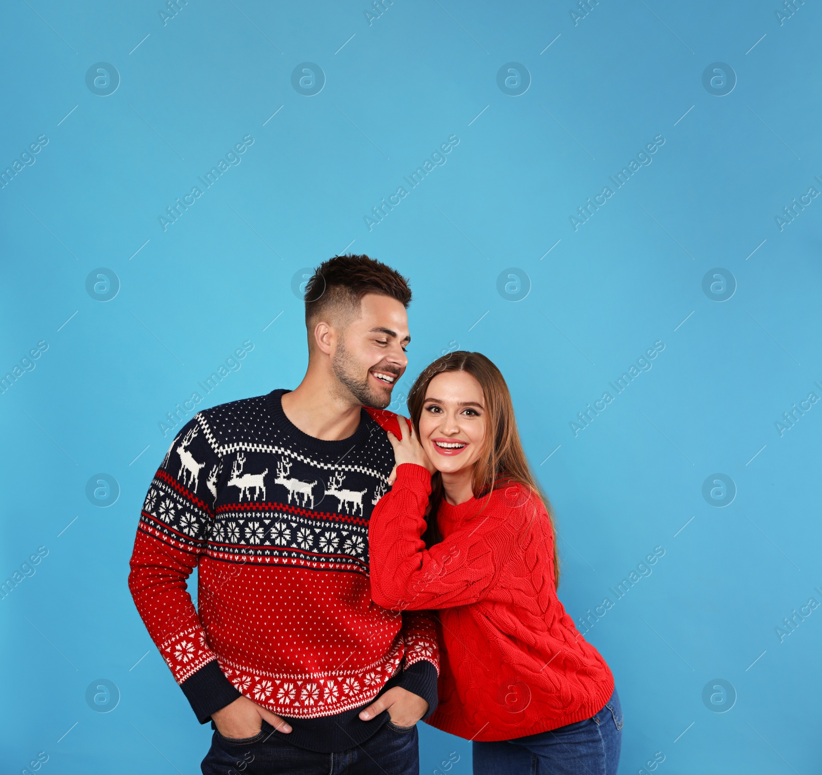 Photo of Couple wearing Christmas sweaters on blue background