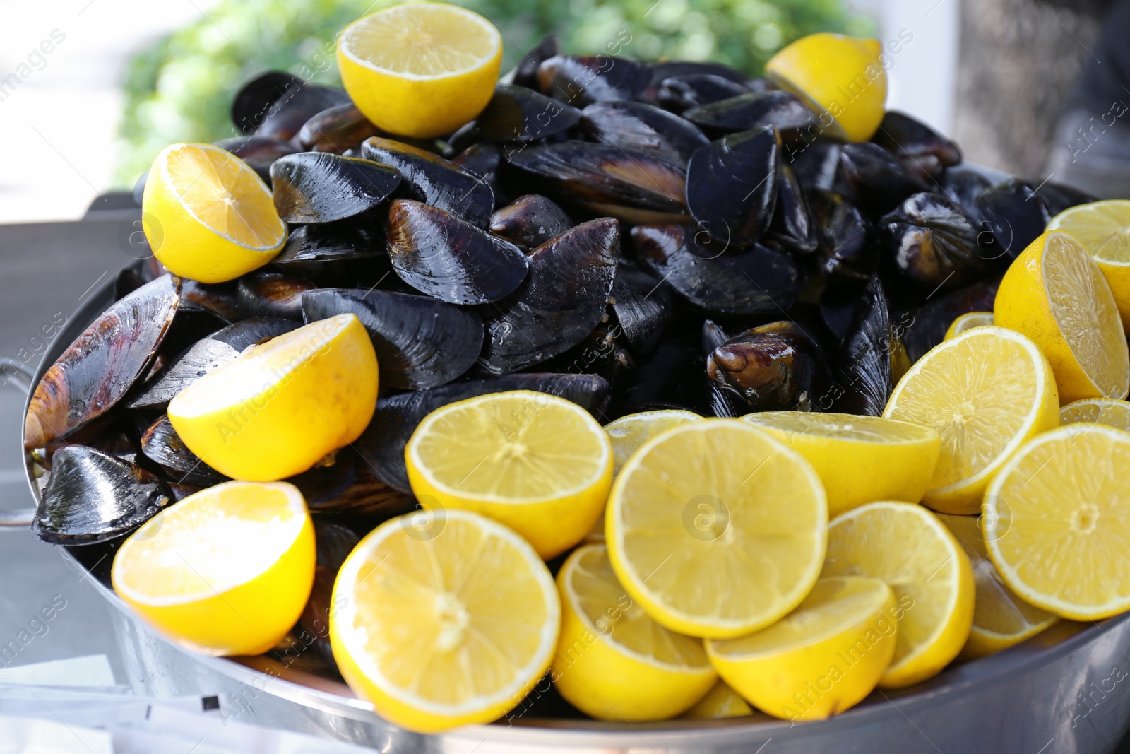 Photo of Stewpan with fresh mussels and lemons, closeup