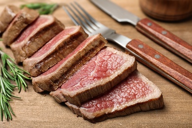 Photo of Cut roasted meat with rosemary on wooden background, closeup
