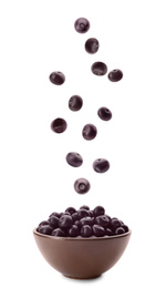 Image of Fresh acai berries falling into bowl on white background