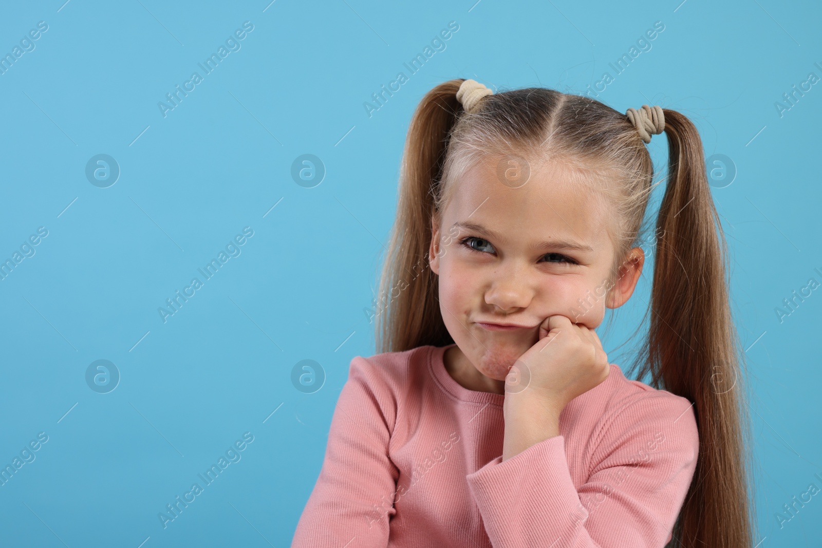 Photo of Resentful girl on light blue background. Space for text