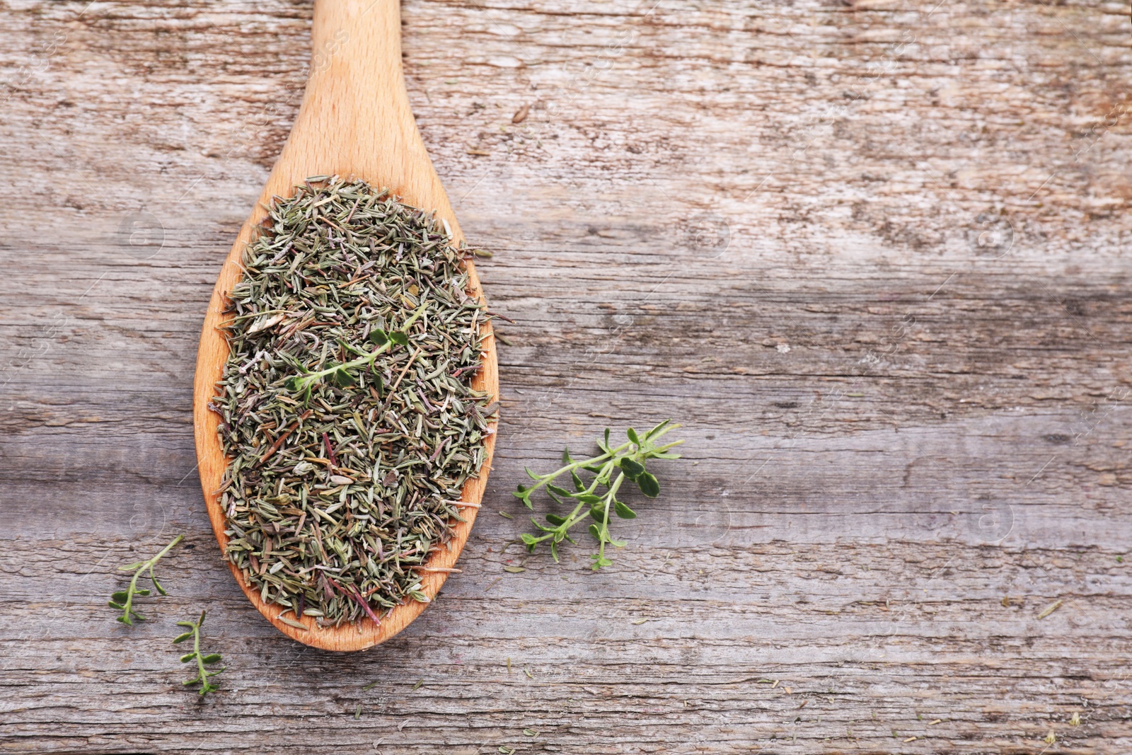 Photo of Spoon with dried and fresh thyme on wooden table, top view. Space for text