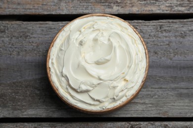 Photo of Bowl of tasty cream cheese on wooden table, top view