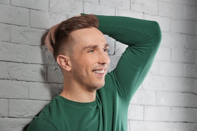 Photo of Portrait of young man with beautiful hair on brick wall background