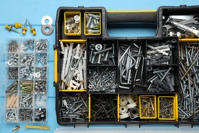 Photo of Organizers with many different fasteners and wrenches on light blue wooden table, flat lay
