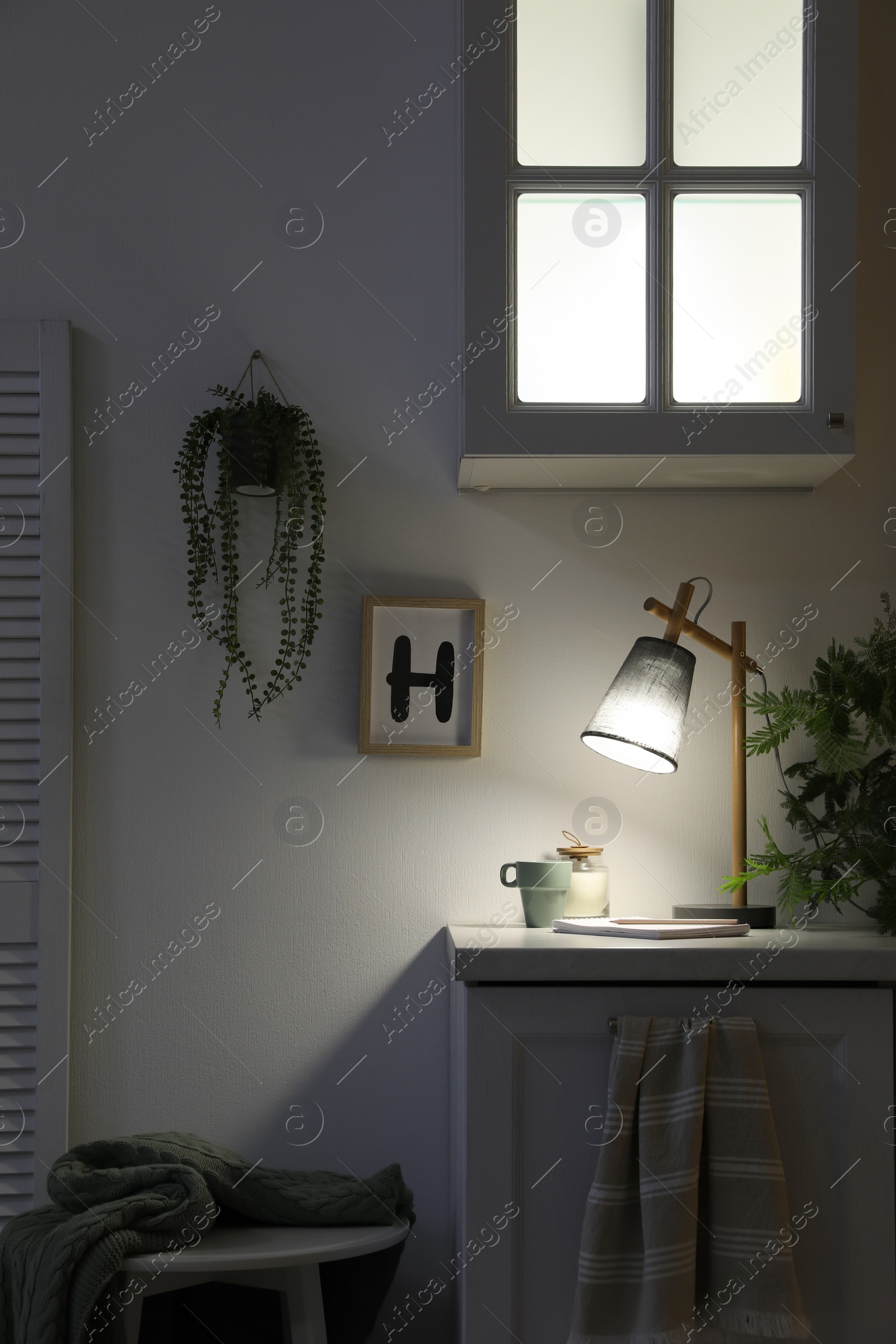 Photo of Stylish lamp and decor on white cabinet in room. Interior element